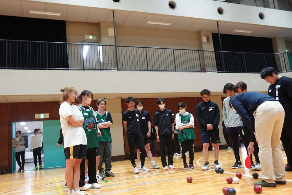 江戸川区パラスポーツ課の方からボッチャの説明を真剣に聞く学生たち